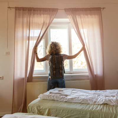 airbnb mini split a backpacker standing in front of a wide window in an airbnb