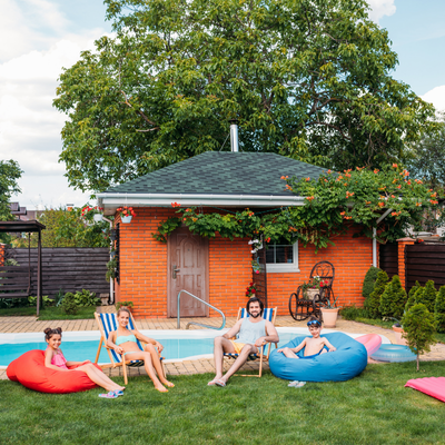 pool house mini split a family lounging on the grass by their pool and pool house